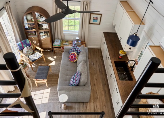 loft view of a 14x22 pool house interior with ceiling fan, hanging light, kitchenette with custom wood countertop, and couch