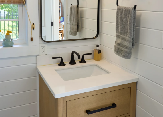 sink and mirror in pool house bathroom with white tongue and groove walls