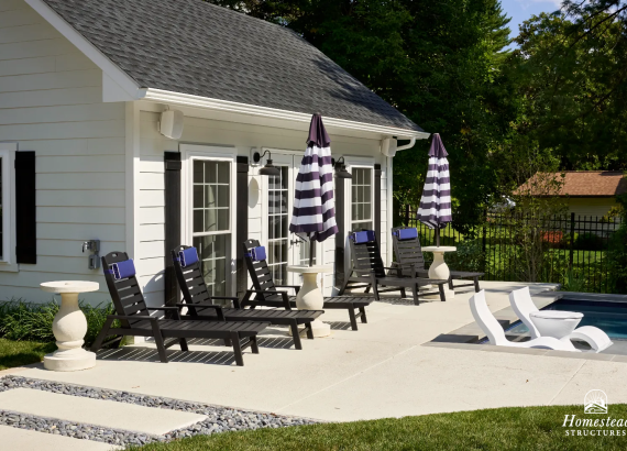 14x22 white pool house with black shutters and french doors in front of an in-ground swimming pool