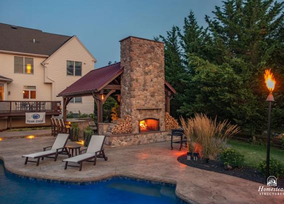 Twilight photo of 16' x 20' Custom Timber Frame Pavilion with Double Sided Fireplace & Lean-To Shed in Orefield PA